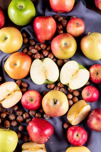 Vista superior de manzanas con nueces sobre tela gris en vertical de madera marrón