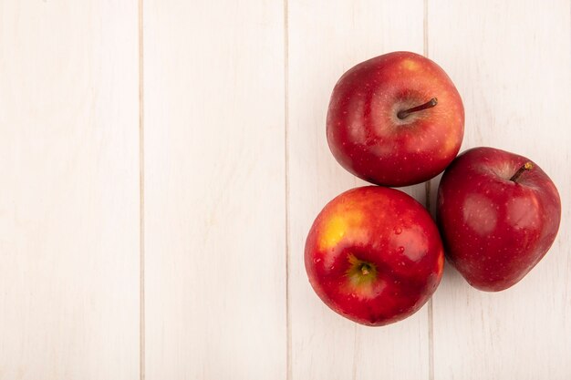 Vista superior de manzanas rojas frescas aisladas sobre una superficie de madera blanca con espacio de copia