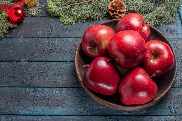 Vista superior de manzanas rojas frescas frutas maduras suaves en un escritorio azul oscuro planta muchos árboles de frutas de color rojo fresco