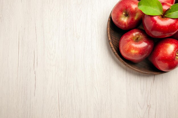 Vista superior de manzanas rojas frescas frutas maduras y suaves en el escritorio blanco árbol de color de fruta planta fresca roja