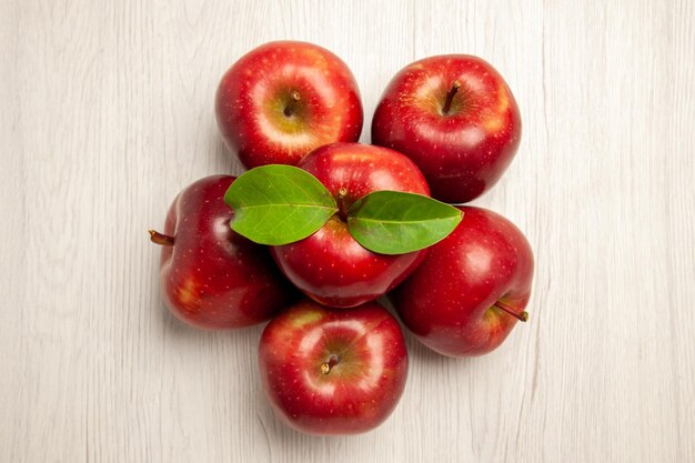 Vista superior de manzanas rojas frescas frutas maduras y suaves en el escritorio blanco color de la fruta planta fresca árbol rojo