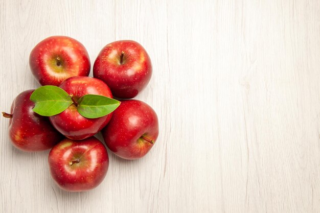 Vista superior de manzanas rojas frescas frutas maduras y suaves en el escritorio blanco frutas color planta fresca árbol rojo