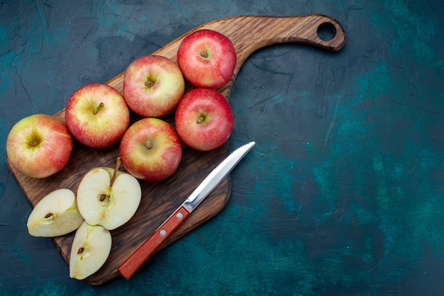 Vista superior de manzanas rojas frescas jugosas y suaves con escritorio marrón sobre el fondo azul oscuro fruta fresca vitamina suave madura