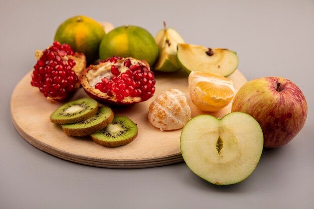 Vista superior de manzanas saludables con frutas como mandarinas de kiwi de granada en una tabla de cocina de madera