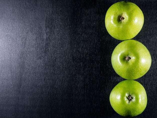 Vista superior de manzanas verdes con espacio de copia a la izquierda en horizontal de madera negra