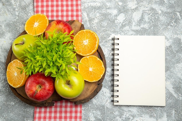 Foto gratuita vista superior de manzanas verdes frescas con naranjas en rodajas sobre la superficie blanca fruta de manzana suave madura fresca