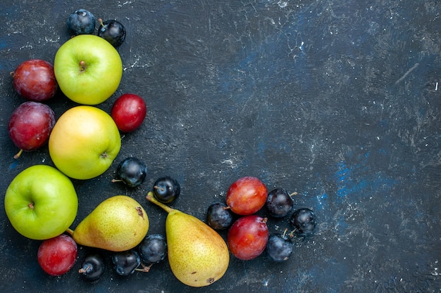 Vista superior de manzanas verdes frescas con peras endrinas y ciruelas en azul oscuro, fruta fresca comida suave