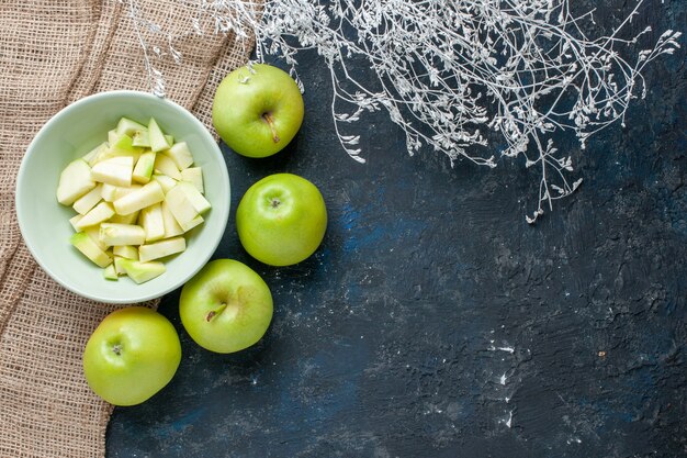 Vista superior de manzanas verdes frescas suaves y jugosas con rodajas de manzana dentro de la placa en azul oscuro, frutas alimentos frescos vitamina salud