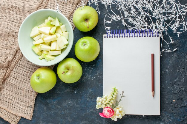 Vista superior de manzanas verdes frescas suaves y jugosas con rodajas de manzana dentro de la placa en el piso oscuro, frutas, alimentos frescos, vitaminas para la salud