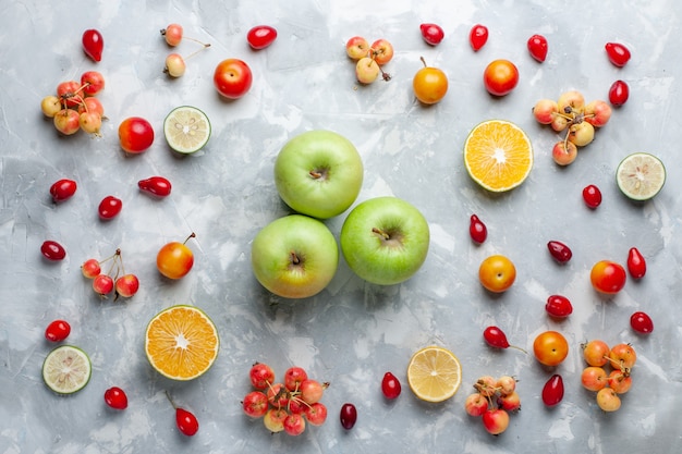 Vista superior de manzanas verdes con limón y cerezas en el escritorio blanco fruta baya vitamina verano suave