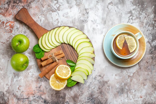 Vista superior de manzanas verdes en rodajas con una taza de té sobre fondo claro