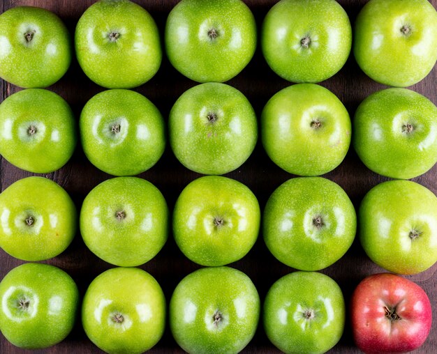 Vista superior de manzanas verdes y una roja en el patrón de esquina en horizontal de madera negra