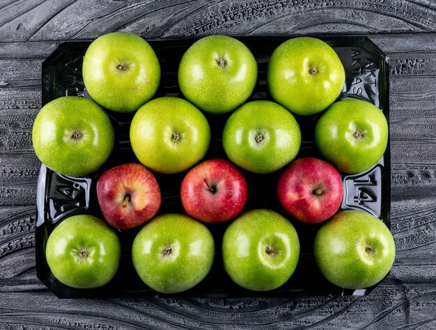 Vista superior manzanas verdes y rojas en horizontal de madera gris