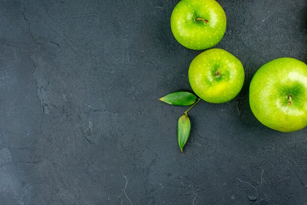 Vista superior de manzanas verdes sobre superficie oscura con espacio de copia