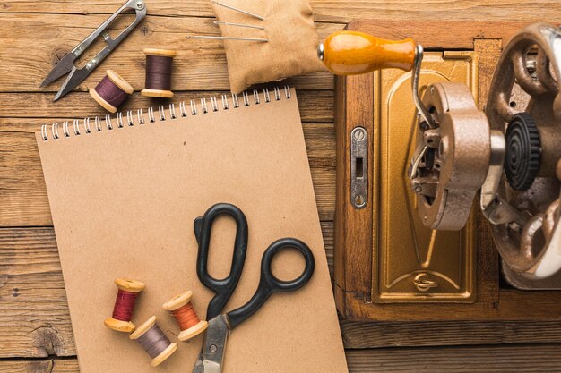 Vista superior de la máquina de coser vintage con cuaderno y tijeras