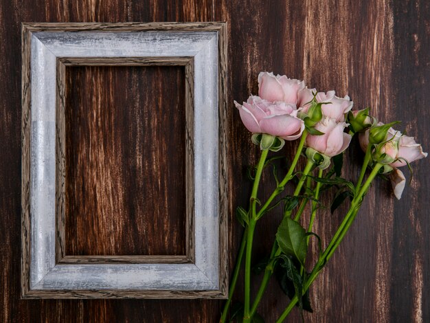 Vista superior del marco gris con rosas rosadas sobre una superficie de madera