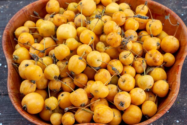 Vista superior más cercana de las cerezas frescas amarillas dulce, suave y jugosa placa interior en gris