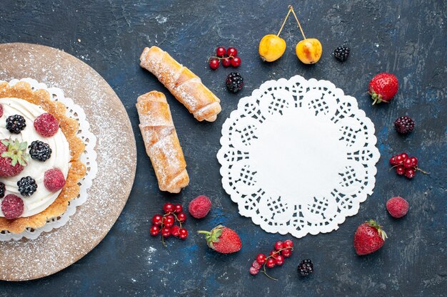 Vista superior más cercana del delicioso pastelito con crema de azúcar en polvo y bayas junto con brazaletes en la oscuridad