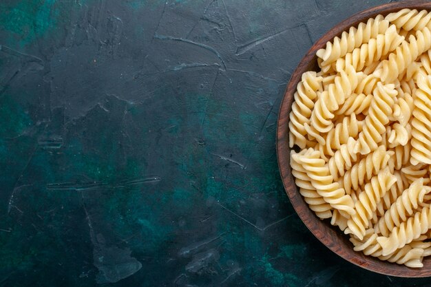 Vista superior más cercana pasta italiana deliciosa mirando dentro de una olla marrón en el escritorio azul oscuro