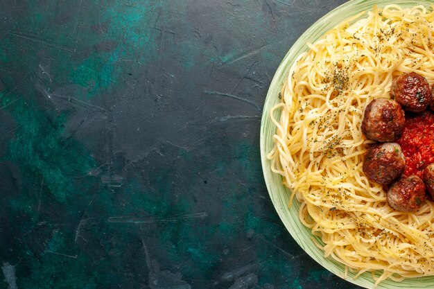 Vista superior más cercana sabrosa pasta italiana con albóndigas en la superficie azul oscuro