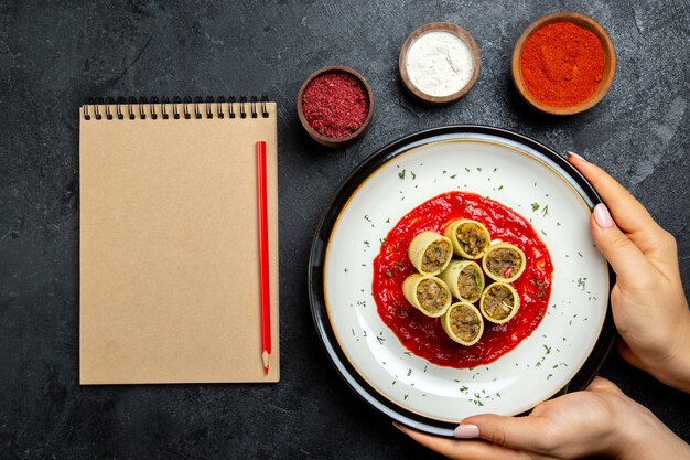 Vista superior de masa con carne en rodajas con salsa de tomate y condimentos en el espacio gris