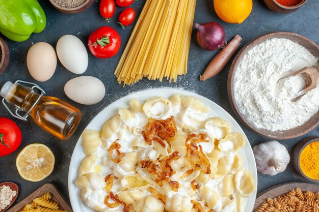 Vista superior de masa cocida con pasta cruda, verduras, condimentos y huevos sobre fondo oscuro, color, aceite, calorías, alimentos, huevo, leche, masa, cena, comida