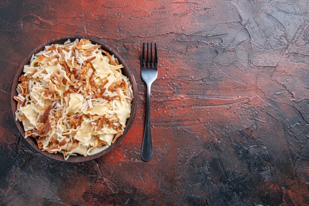 Vista superior de la masa cocida en rodajas con arroz en la masa de plato de pasta de comida de piso oscuro