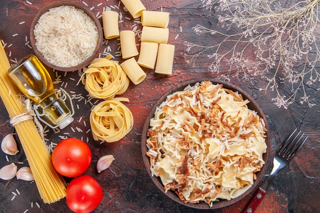 Vista superior de la masa cocida en rodajas con arroz en la oscuridad de la masa de plato de pasta de escritorio oscuro