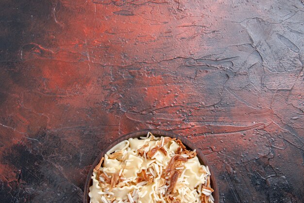 Vista superior de la masa cocida en rodajas con arroz en la superficie oscura de la masa del plato de pasta