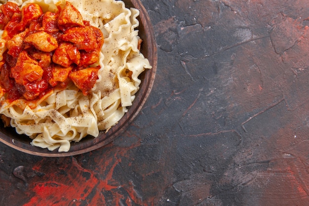 Foto gratuita vista superior de la masa cocida con rodajas de pollo y salsa sobre la masa de pasta de superficie oscura plato oscuro