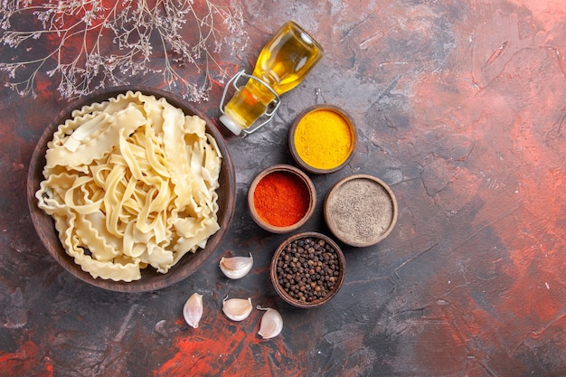 Vista superior de masa cruda en rodajas con condimentos en el escritorio oscuro comida de pasta de masa oscura