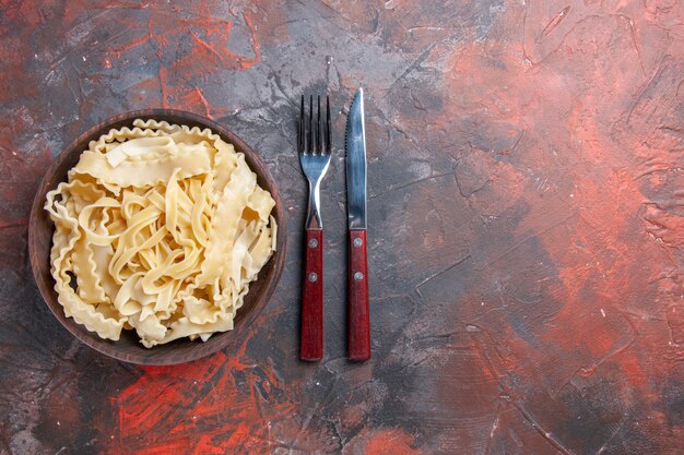 Foto gratuita vista superior de la masa cruda en rodajas dentro de la placa sobre la superficie oscura pasta cruda comida oscura