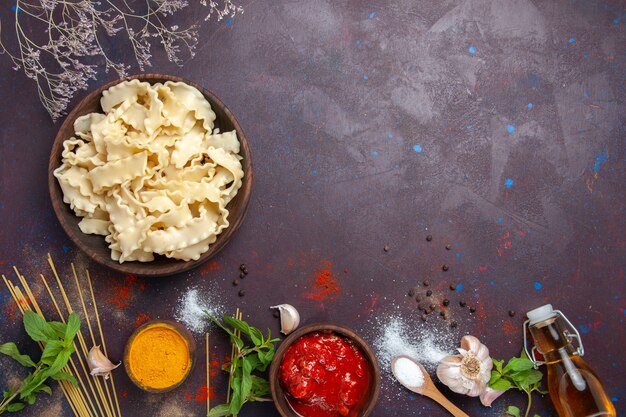 Vista superior de masa cruda en rodajas con salsa de tomate sobre fondo oscuro comida cena pasta pasta