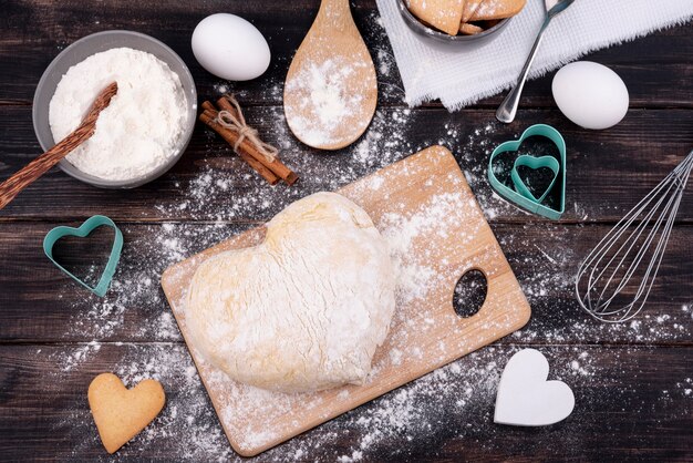 Vista superior de masa en forma de corazón con utensilios de cocina.