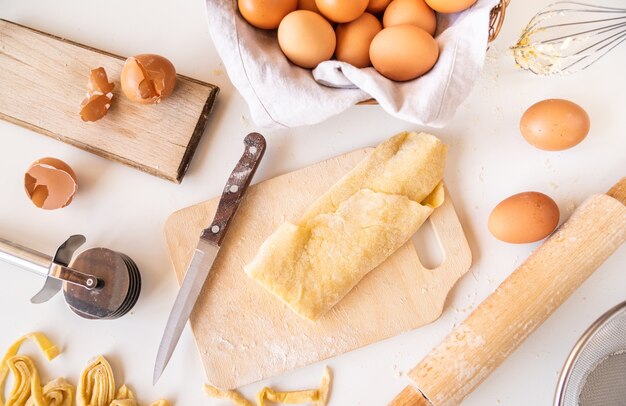 Vista superior de masa de pasta con ingredientes y suministros alrededor