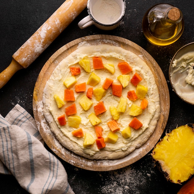 Vista superior de la masa de pizza con cubos de piña y papaya