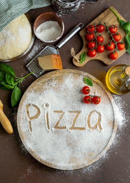 Foto gratuita vista superior de la masa de pizza con tablero de madera y palabra escrita en harina