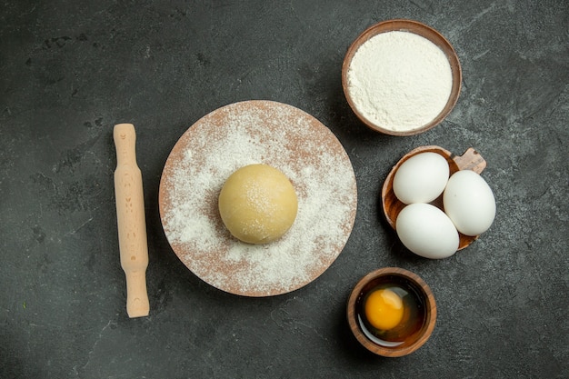 Vista superior de masa redonda cruda con harina y huevos sobre fondo gris harina de masa de alimentos harina cruda