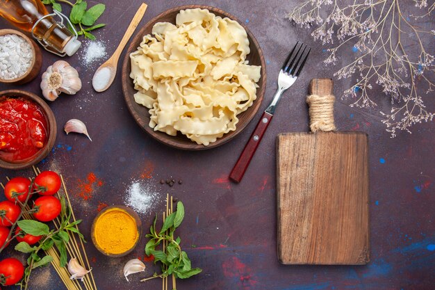 Vista superior de masa en rodajas con salsa de tomate y tomates en el fondo oscuro cena de pasta de comida de masa de comida