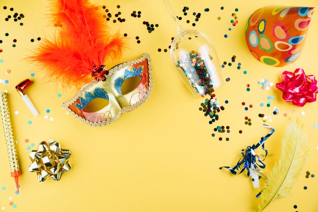 Vista superior de la máscara de carnaval con material de decoración y sobre fondo amarillo