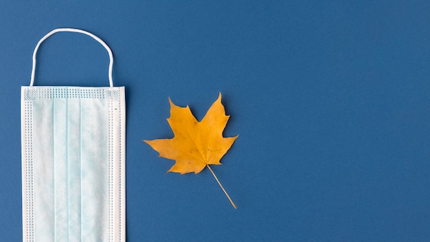 Vista superior de la máscara médica con hoja de otoño