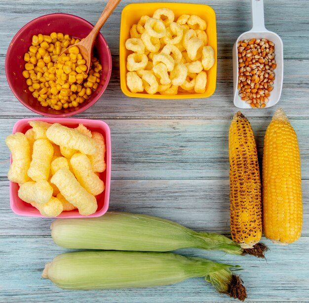 Vista superior de mazorcas de maíz con cereales pop de maíz y semillas de maíz en superficie de madera