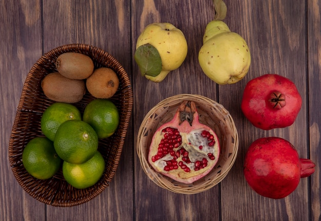 Foto gratuita vista superior media granada en canasta con peras, mandarinas y kiwi en pared de madera