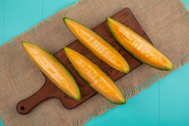Foto gratuita vista superior de melón cantalupo fresco y saludable en tablero de cocina de madera en tela de saco en azul