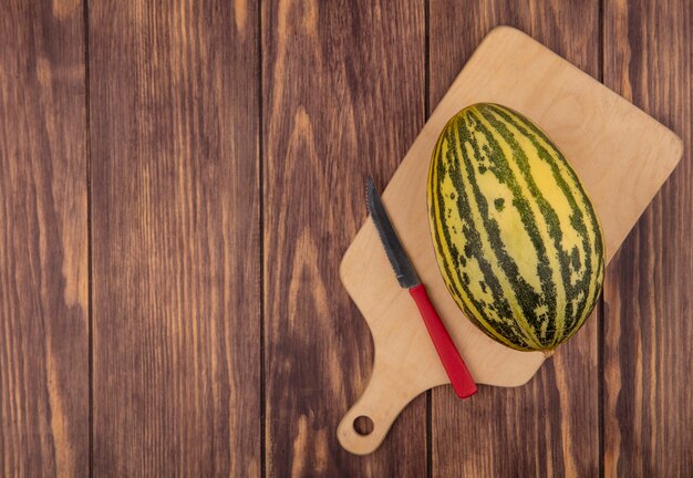 Vista superior del melón cantalupo fresco en una tabla de cocina de madera con un cuchillo en una pared de madera con espacio de copia