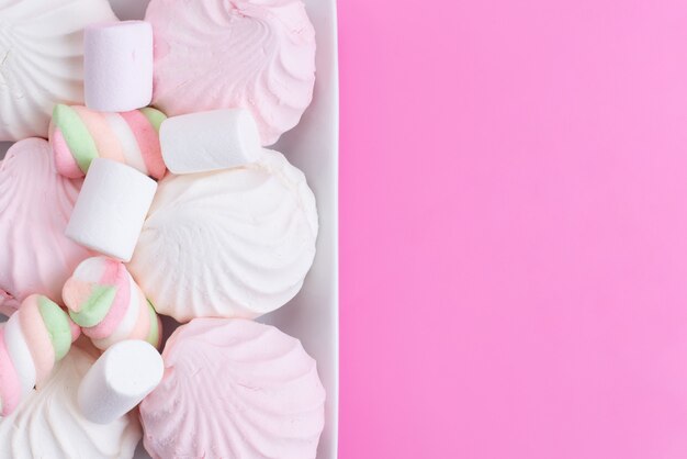 Una vista superior de merengues y malvaviscos dulces y deliciosos en rosa, galleta dulce azúcar dulce