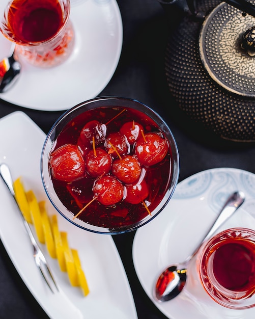 Vista superior de mermelada de manzanas del paraíso en un florero de vidrio sobre la mesa servida con té