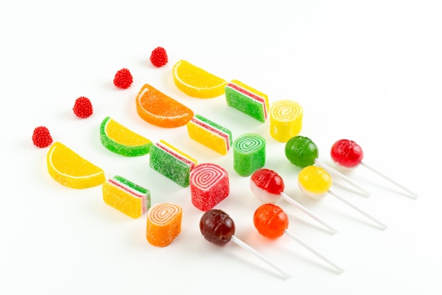 Una vista superior de mermelada y piruletas de colores dulces pegajosos en blanco, confitura de azúcar de color