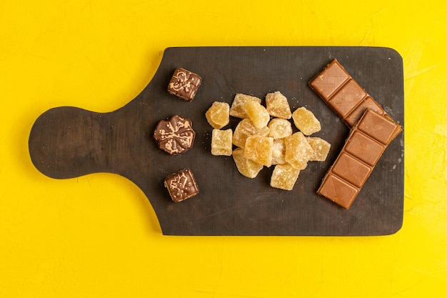 Foto gratuita vista superior de mermelada en rodajas dulce y confituras en rodajas de azúcar con barras de chocolate sobre superficie amarilla