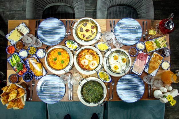 Vista superior de la mesa de desayuno de huevos fritos con hierbas, tomates y salchichas